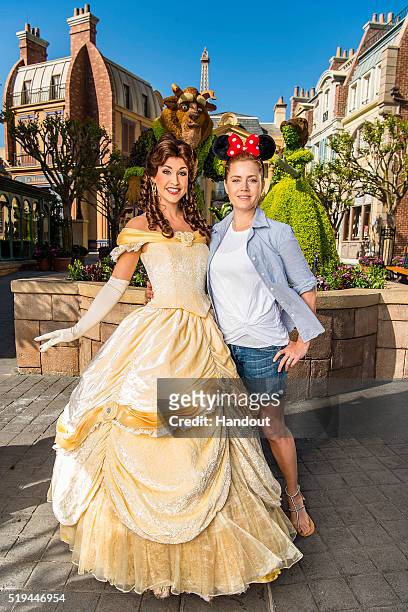 In this handout photo provided by Disney Parks, five-time academy-award-nominated actress Amy Adams poses with princess Belle at the Epcot...