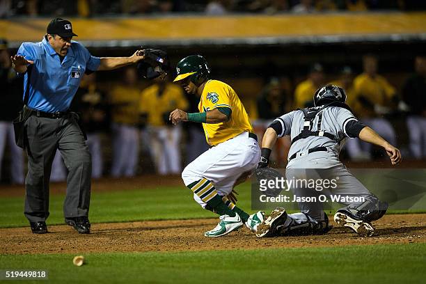Khris Davis of the Oakland Athletics slides into home plate ahead of a tag from Alex Avila of the Chicago White Sox to score a run in front of umpire...