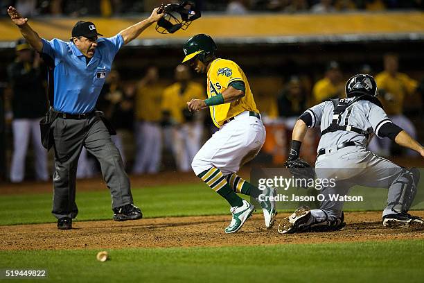 Khris Davis of the Oakland Athletics slides into home plate ahead of a tag from Alex Avila of the Chicago White Sox to score a run in front of umpire...