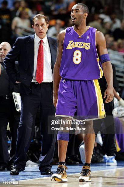Kobe Bryant of the Los Angeles Lakers walks back onto the court with head coach Rudy Tomjanovich behind him during the first half against the Denver...