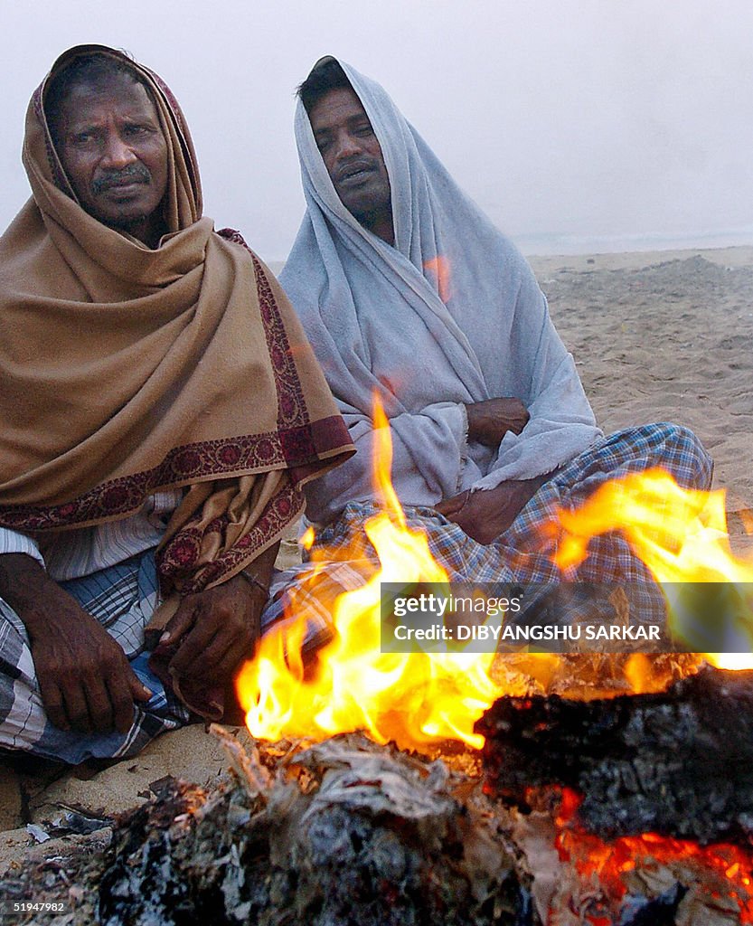 Indian tsunami survivors sit by a fire o