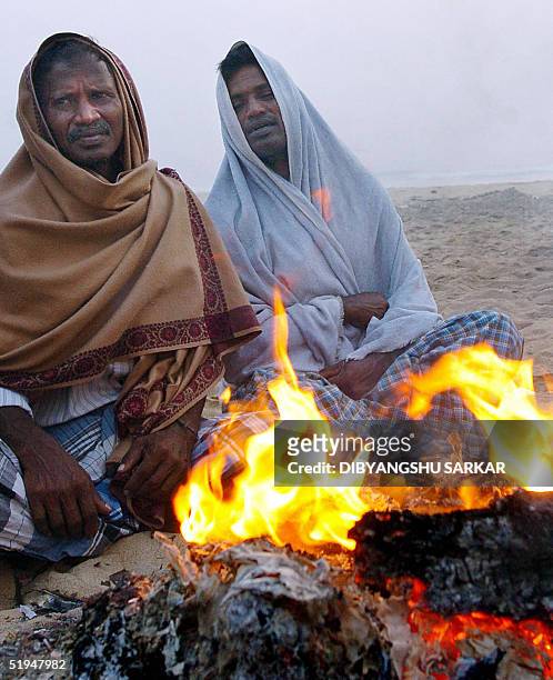 Indian tsunami survivors sit by a fire on the beach in Patinapakkam, near Madras, 13 January 2005. India has said some 10,327 people died in the...