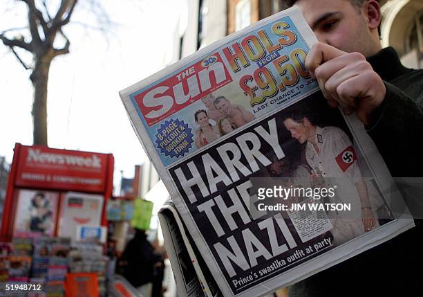 Man reads the newspaper "The Sun" in London 13 January, 2005 with a headline about Prince Harry wearing a Nazi uniform at a costume party. Britain's...