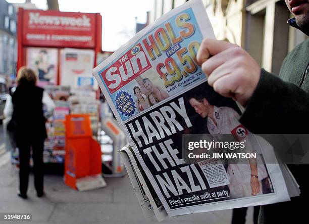 Man reads the newspaper "The Sun" in London 13 January, 2005 with a headline about Prince Harry wearing a Nazi uniform at a costume party. Britain's...