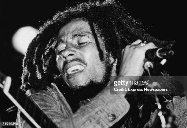 Jamaican reggae musician Bob Marley performs on stage, a microphone in his hand, late 1970s.
