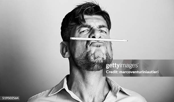 mad artist holds a pencil with his lips - author stockfoto's en -beelden