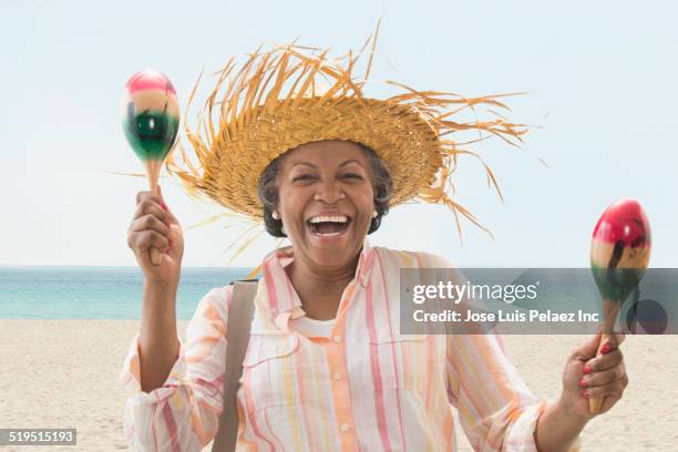 older african american woman playing maracas on beach - maracas stock pictures, royalty-free photos & images