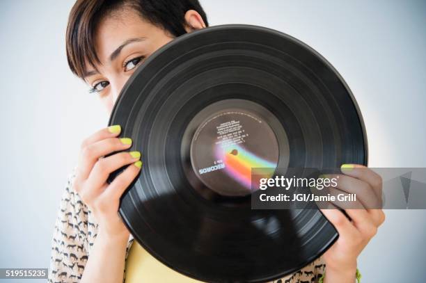 mixed race woman holding vinyl record - looking at a photo album stock-fotos und bilder