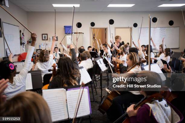 students raising instrument bows in music class - kids instruments fotografías e imágenes de stock