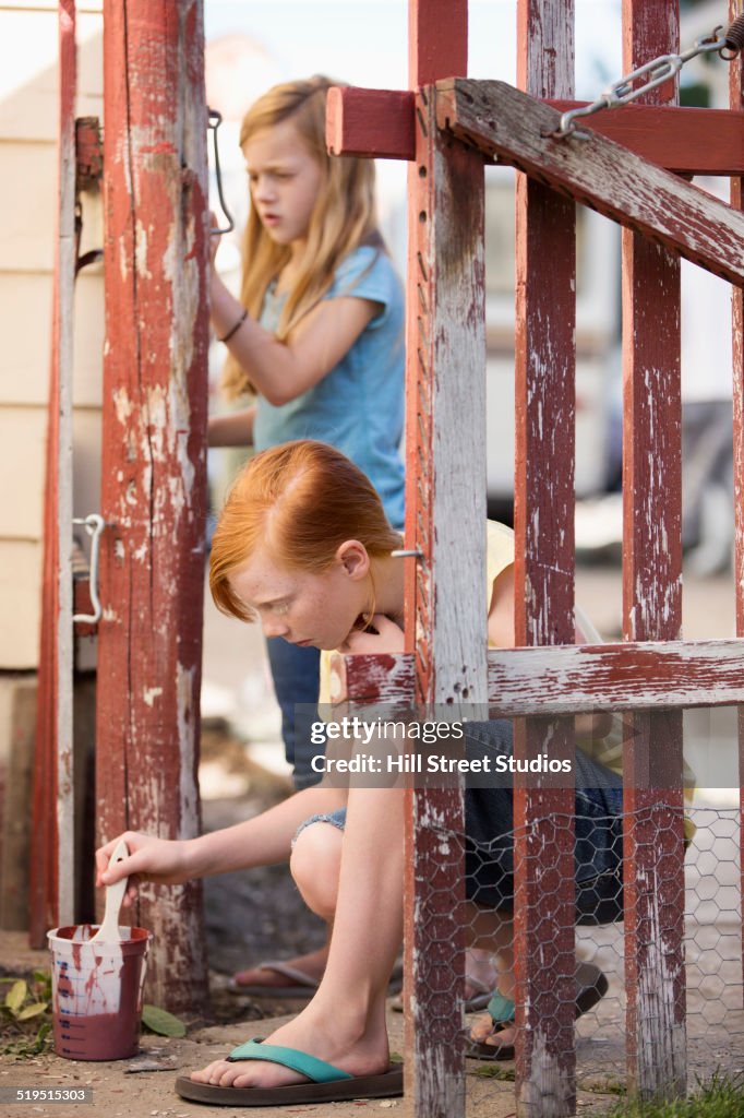 Caucasian girls painting fence