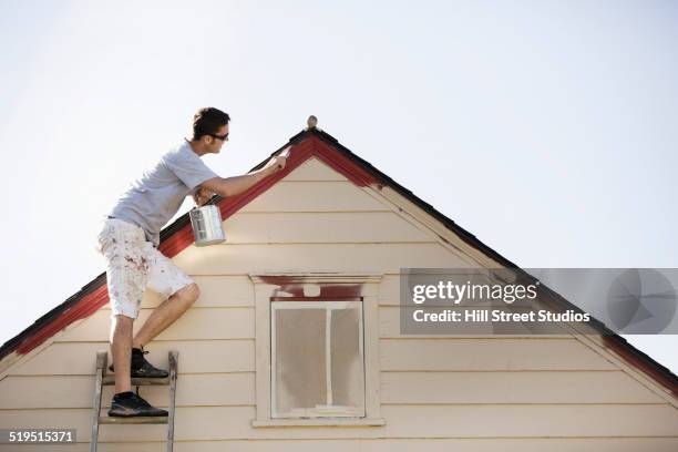 caucasian man painting edge of roof - community health centre stock pictures, royalty-free photos & images