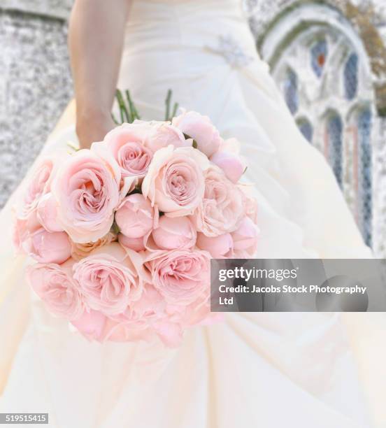 close up of hispanic bride holding bouquet of roses - bride holding bouquet stock pictures, royalty-free photos & images