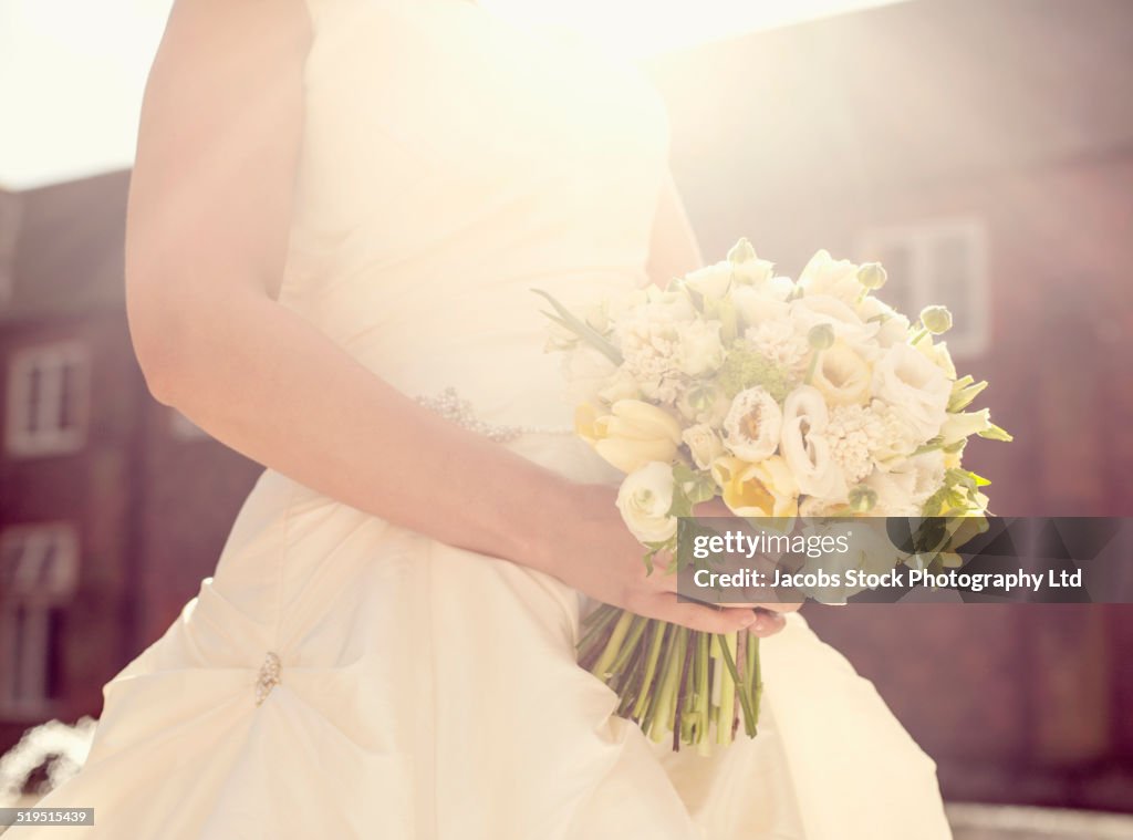 Close up of Hispanic bride holding bouquet of flowers