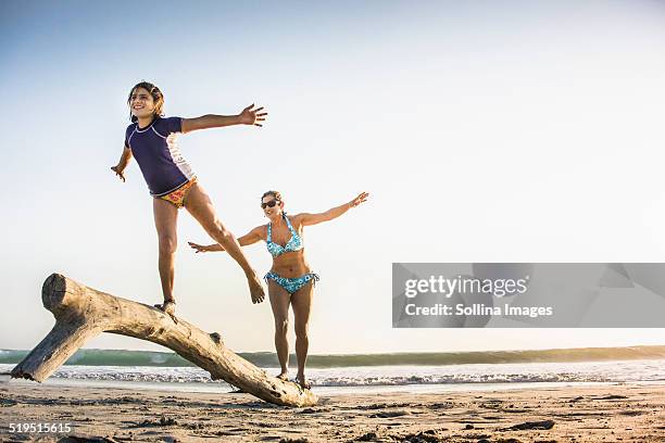 mother and daughter playing on log on beach - hot mexican girls fotografías e imágenes de stock