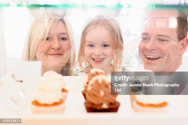 caucasian family admiring cupcakes in bakery window - anticipation excited stock pictures, royalty-free photos & images