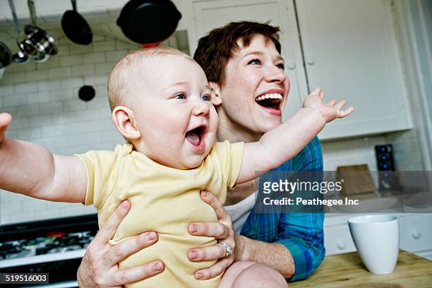 caucasian mother and baby relaxing in kitchen - baby laughing stock pictures, royalty-free photos & images
