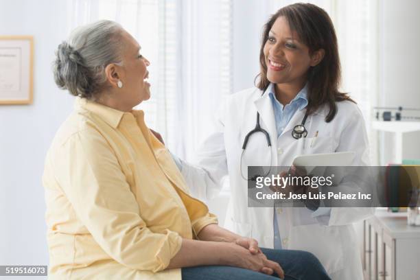older woman talking to doctor in office - healthcare tablet image focus technique stock pictures, royalty-free photos & images