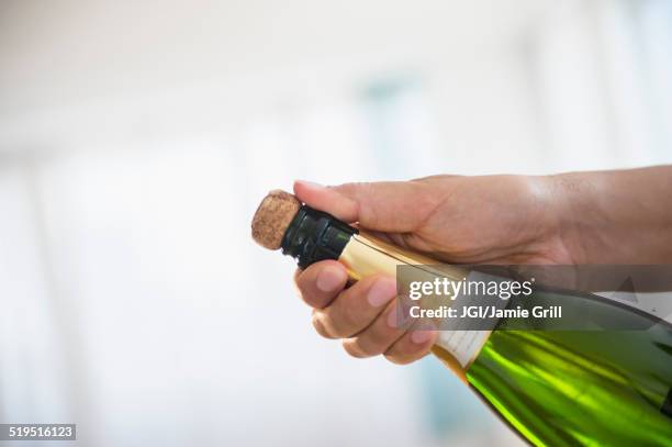 close up of mixed race man opening bottle of champagne - sektkorken stock-fotos und bilder