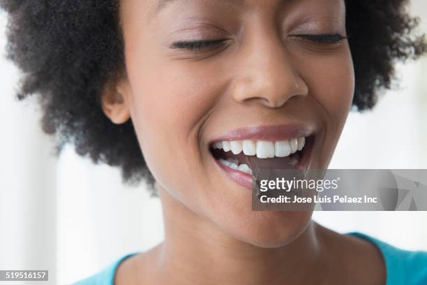 close up of african american woman eating square of chocolate - biting into chocolate stock-fotos und bilder