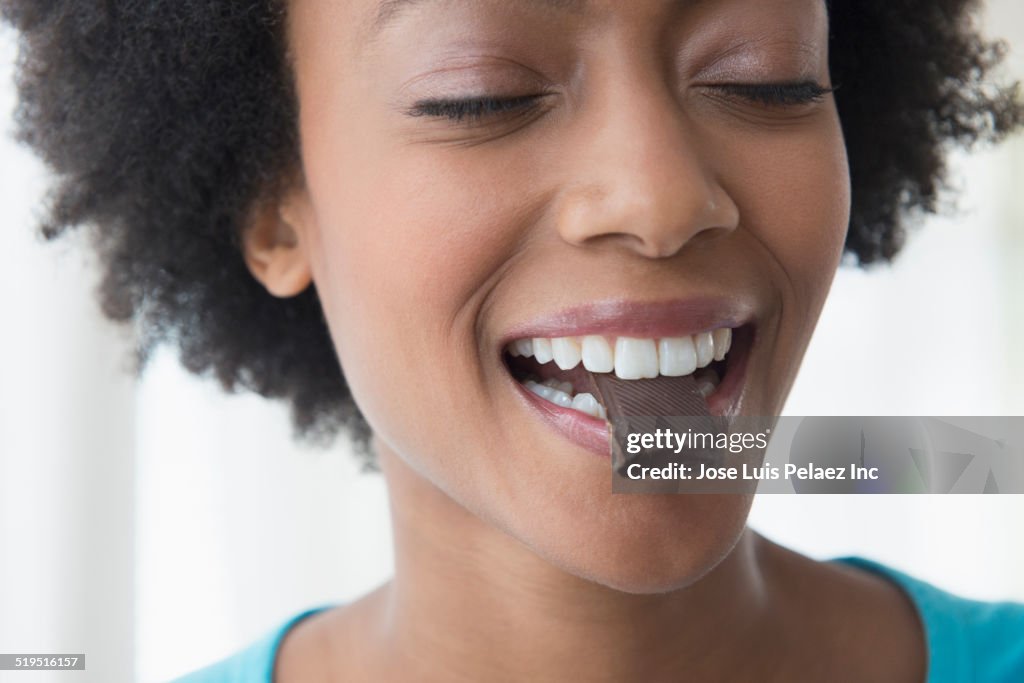 Close up of African American woman eating square of chocolate