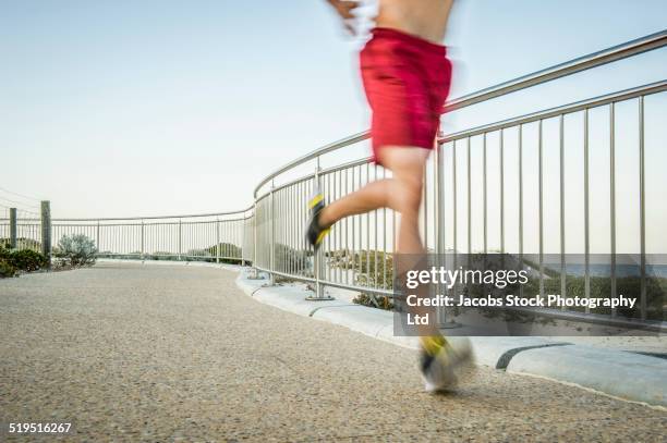 chinese man running on waterfront path - man mid 20s warm stock pictures, royalty-free photos & images