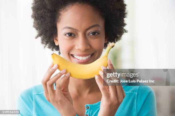 smiling african american woman holding banana - banana woman stock pictures, royalty-free photos & images