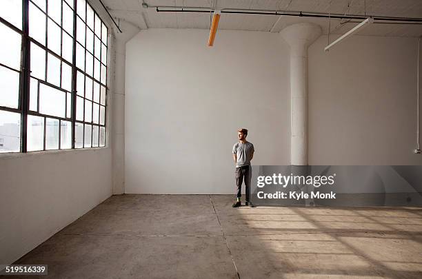 caucasian man standing in empty loft - loft vacio fotografías e imágenes de stock