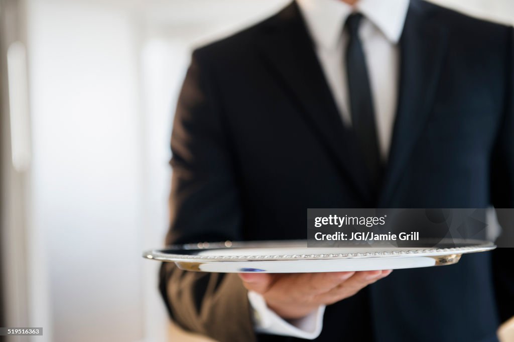 Close up of mixed race waiter holding empty tray