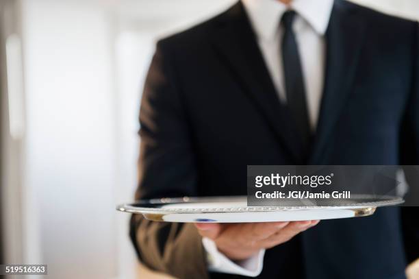 close up of mixed race waiter holding empty tray - butler stock pictures, royalty-free photos & images