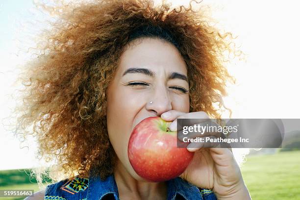 hispanic woman eating apple outdoors - mujer and manzana and frontal fotografías e imágenes de stock