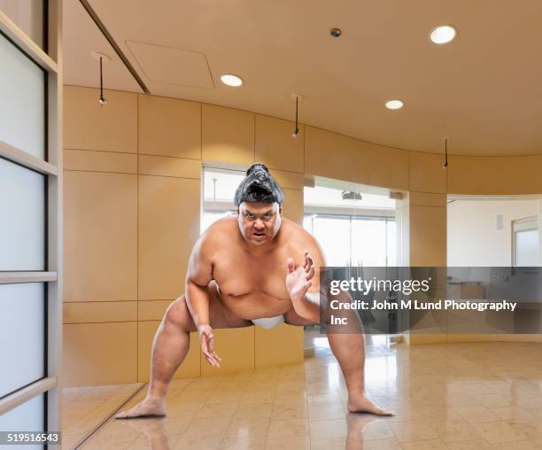 pacific islander sumo wrestler crouching in office - safety funny fotografías e imágenes de stock