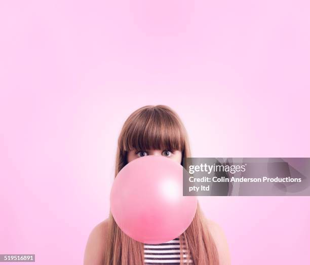 caucasian woman blowing large bubble gum bubble - pusten stock-fotos und bilder