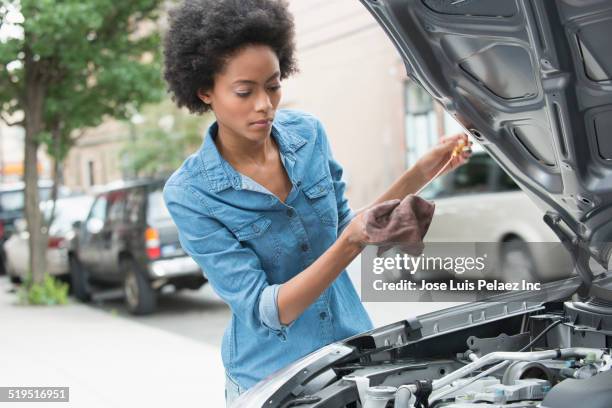 african american woman checking oil of car - dipstick stock pictures, royalty-free photos & images