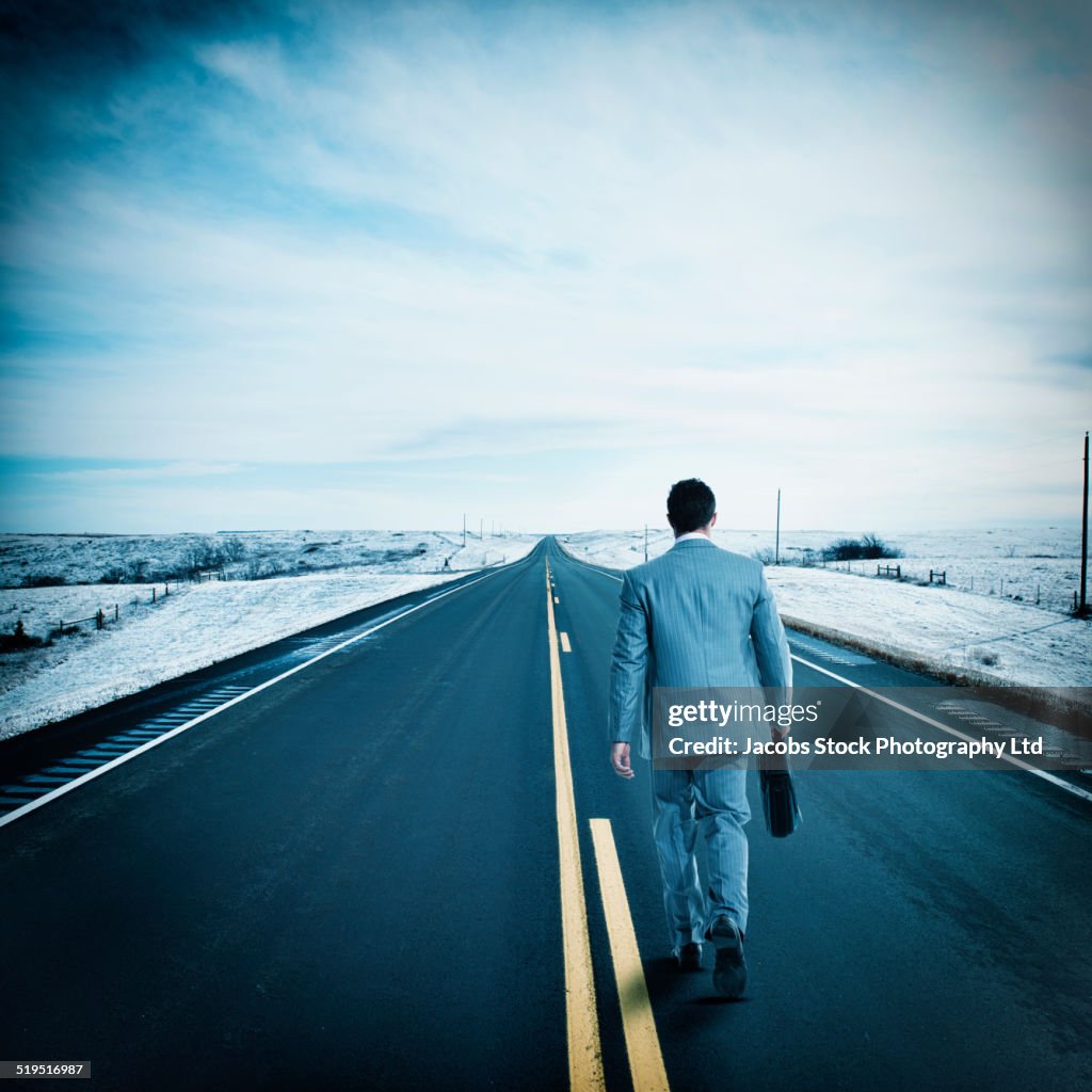 Hispanic businessman walking on remote road