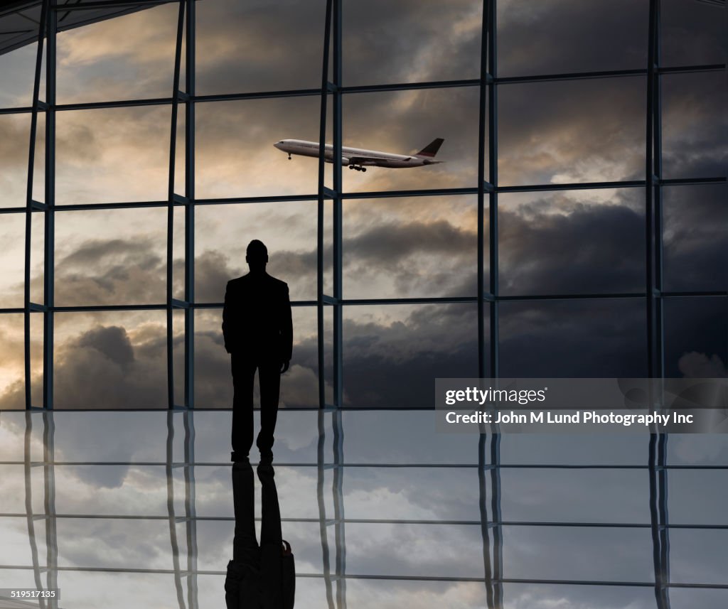 Mixed race businessman standing near window at airport