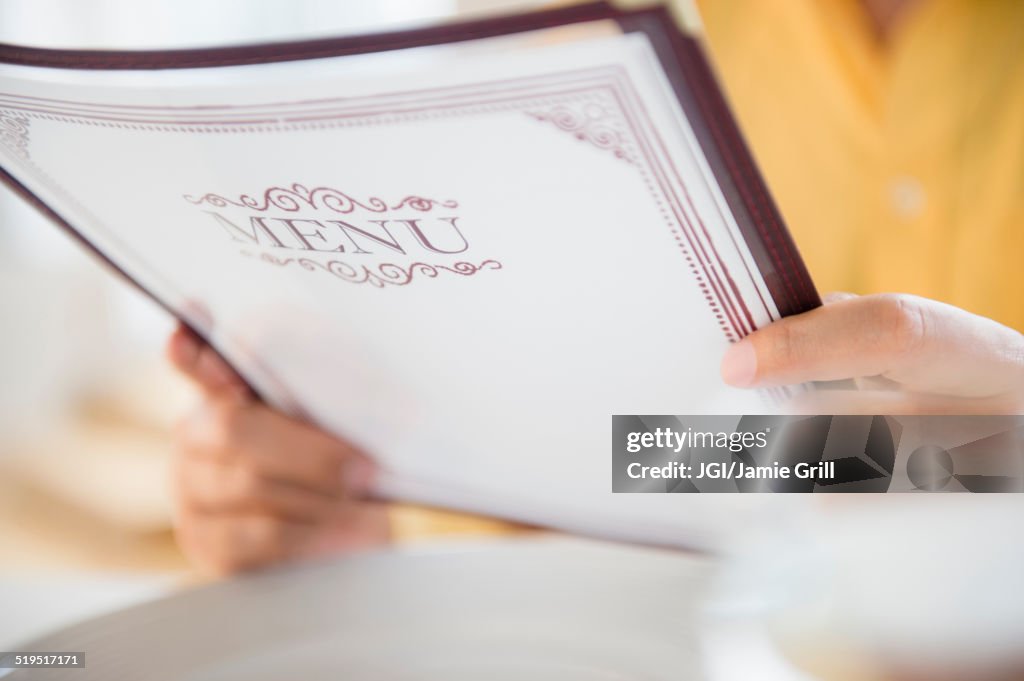 Close up of mixed race man reading menu in restaurant