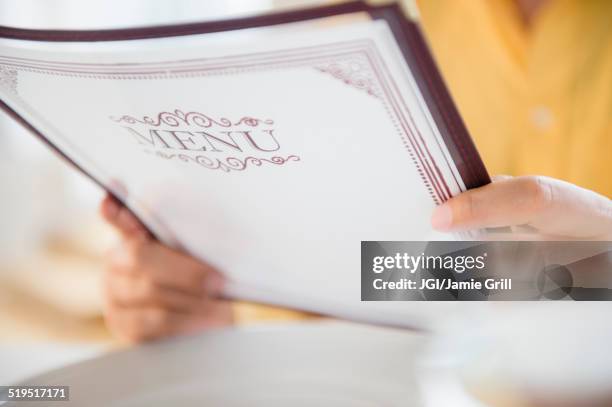 close up of mixed race man reading menu in restaurant - speisekarte stock-fotos und bilder