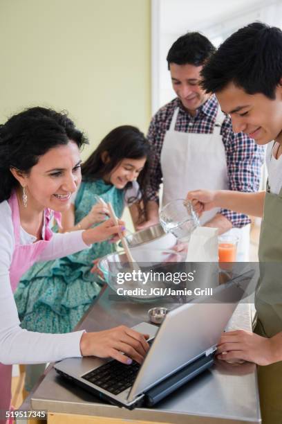 hispanic family baking in kitchen - baking reading recipe stockfoto's en -beelden