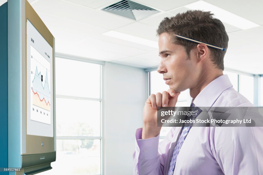 Hispanic businessman reading graph in office