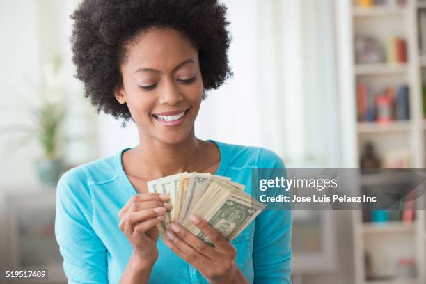 african american woman counting money in living room - african american money stock pictures, royalty-free photos & images