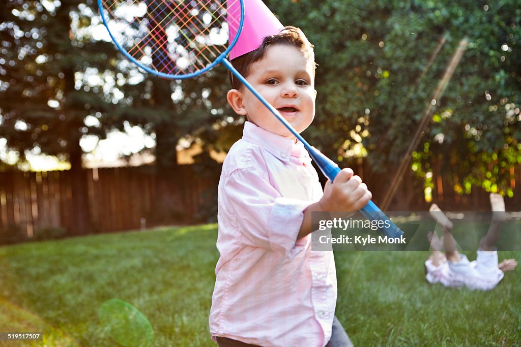 Caucasian children playing badminton in backyard