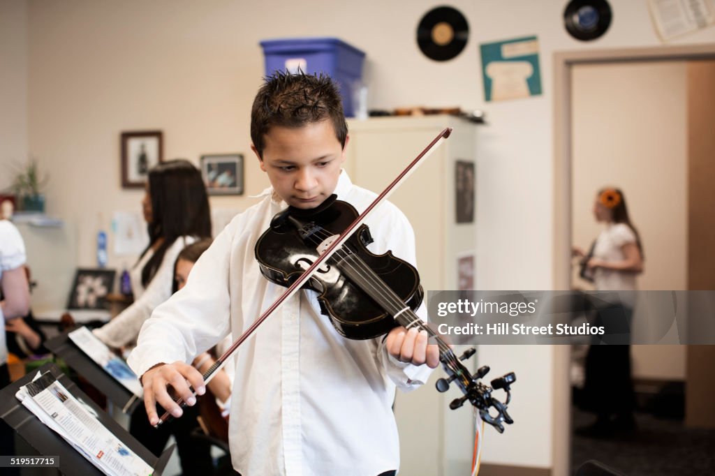 Caucasian boy playing violin in music class