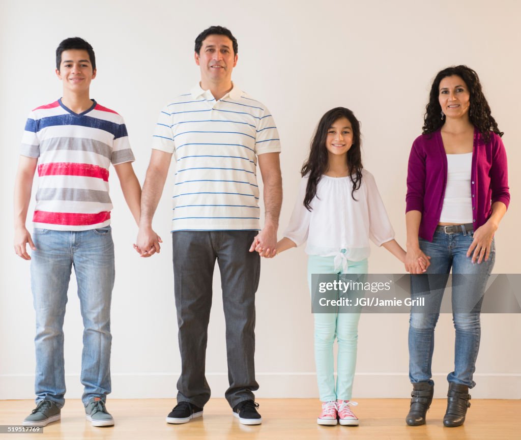 Smiling Hispanic family holding hands