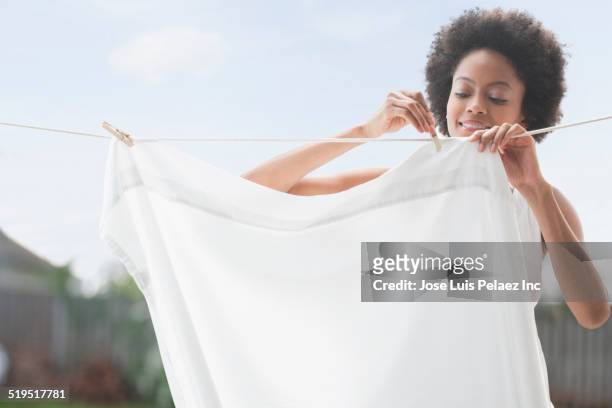 african american woman hanging sheet on clothesline - draped stockfoto's en -beelden