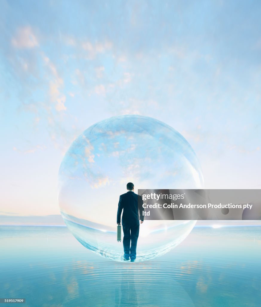 Businessman in bubble walking on water