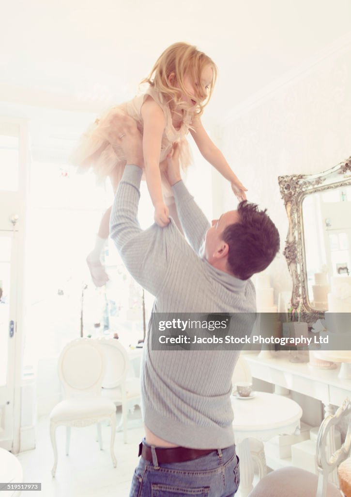 Smiling Caucasian father playing with daughter