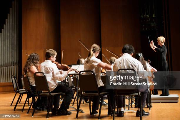 student orchestra playing on stage - conductor stock-fotos und bilder
