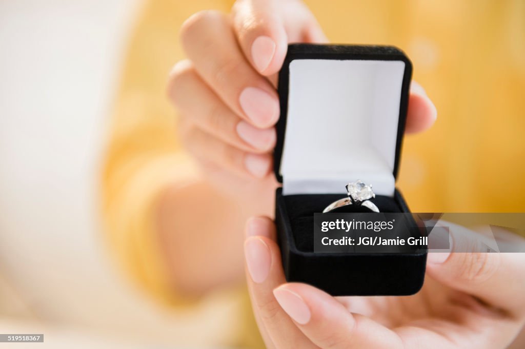 Mixed race man holding engagement ring in box