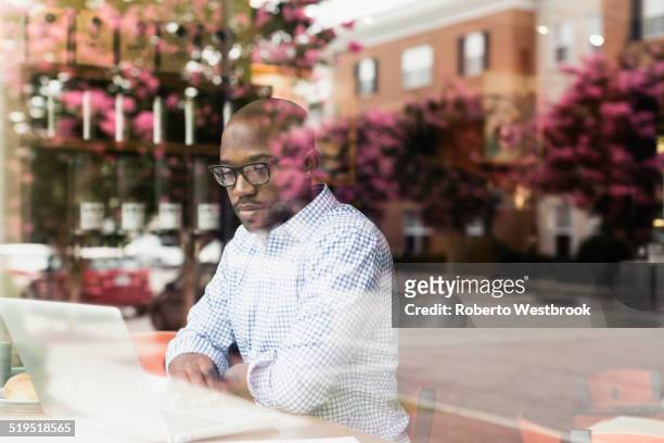 black man using laptop in coffee shop - arbeiten outdoor stadt laptop stock-fotos und bilder