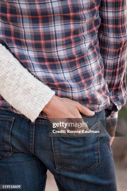 caucasian woman putting hand in pocket of boyfriend - male buttocks stockfoto's en -beelden